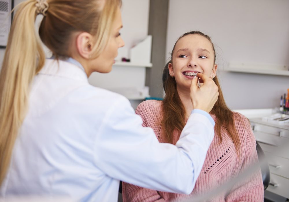 Young orthodontist checking patient in dentist's office